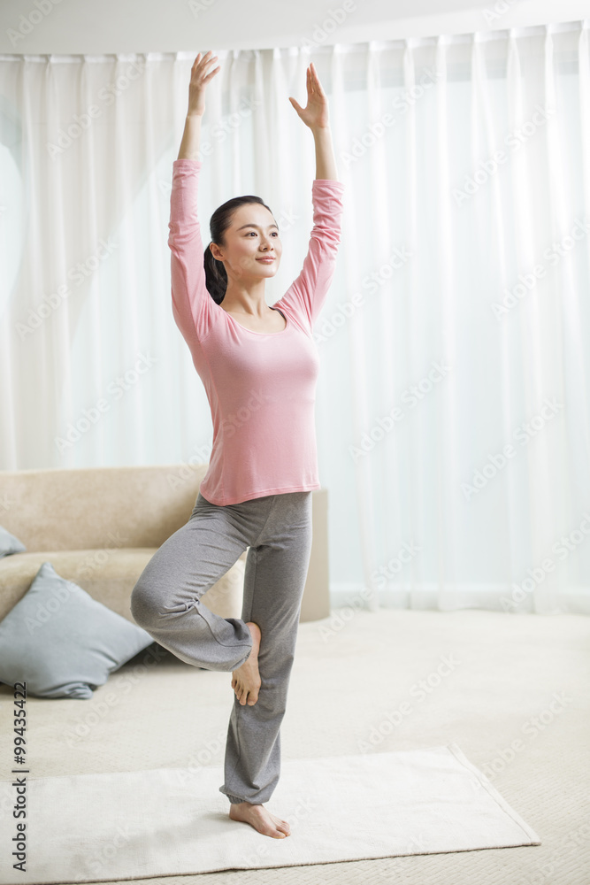 Young woman practicing yoga in living room