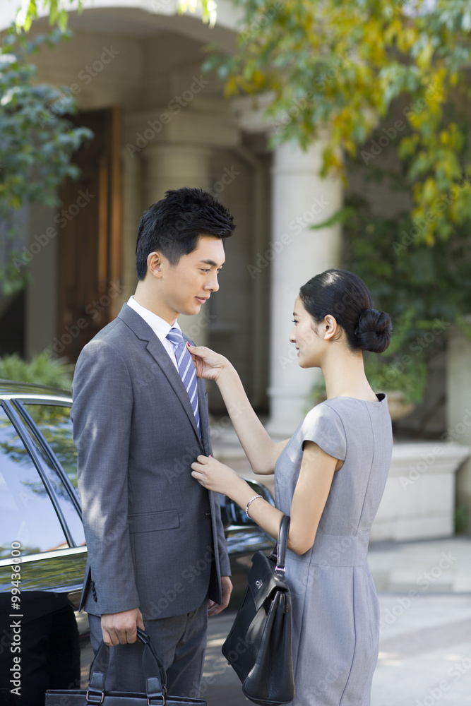 Young woman adjusting her husbands tie