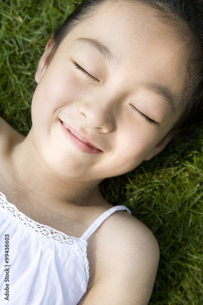 Little girl in white dress playing lying on the grass