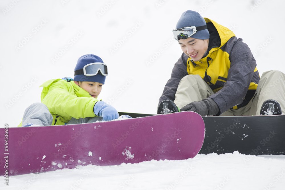 年轻的父子在雪地上玩滑雪板