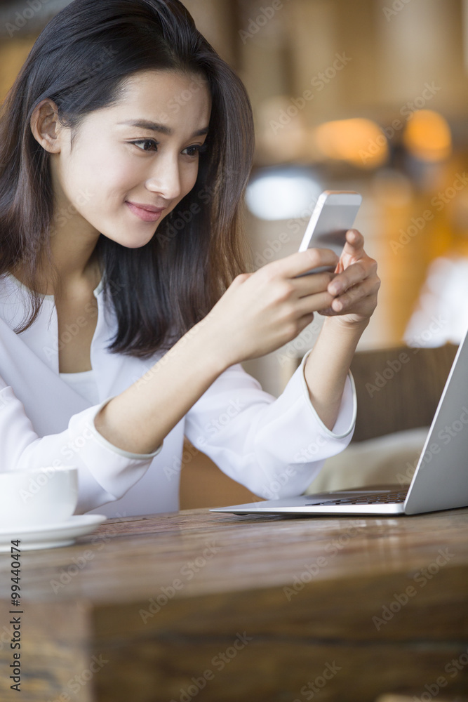 在咖啡馆使用智能手机的年轻女性