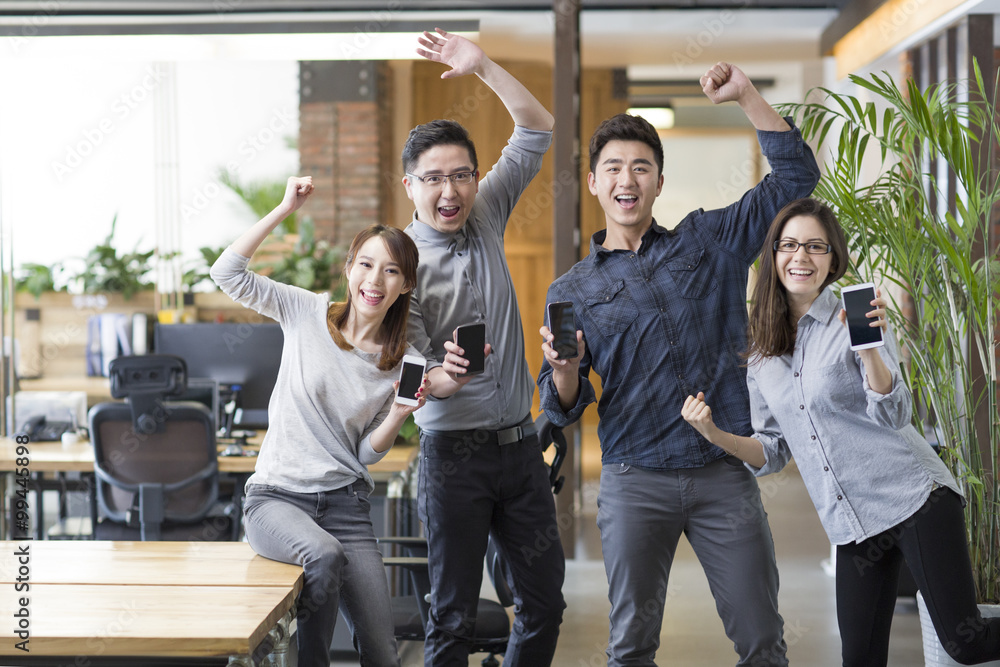 IT workers celebrating with smart phones in office