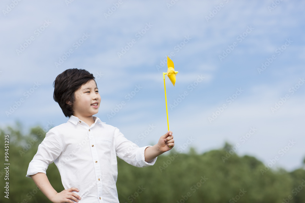 Happy boy playing paper windmill in the open air