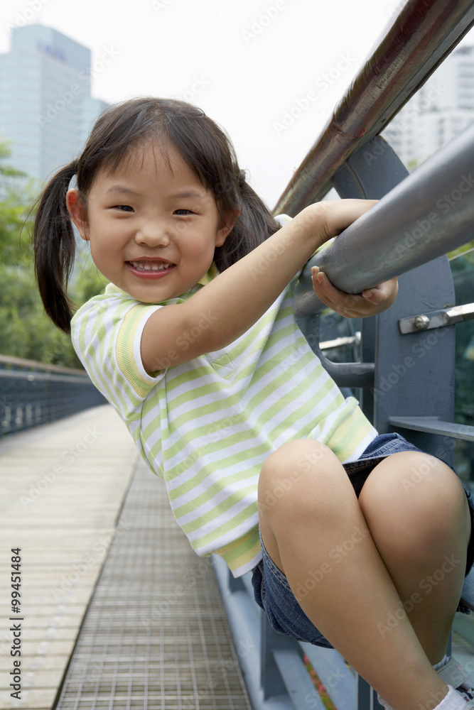 Portrait Of Young Girl Climbing A Bridge In The Park