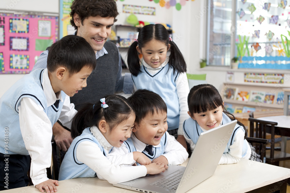 Students and teacher gathered around a computer in the classroom