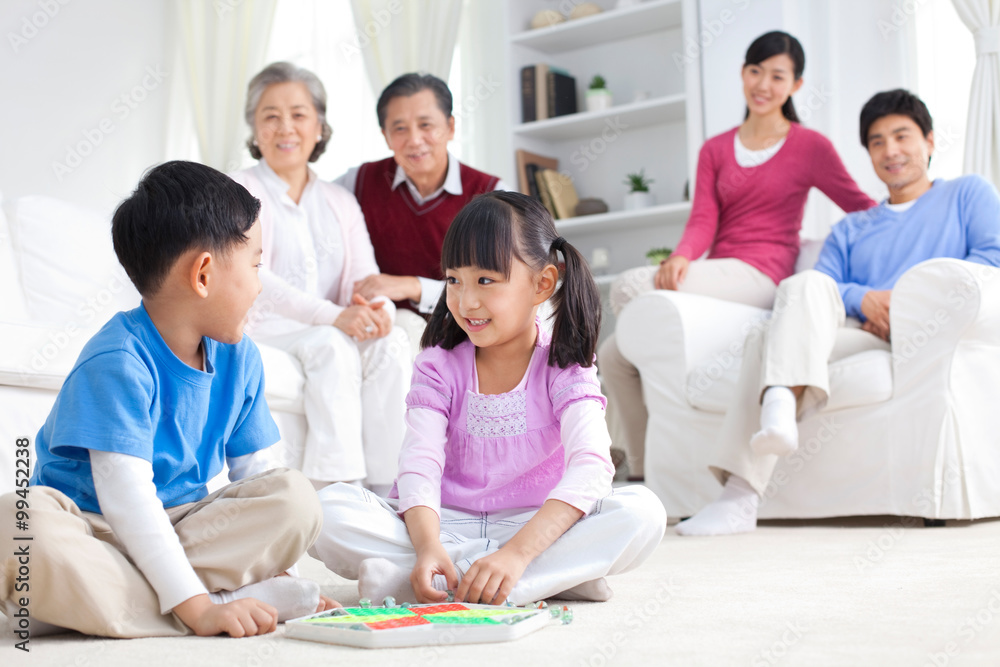 Chinese children playing with toys on the floor with grandparents and parents behind them