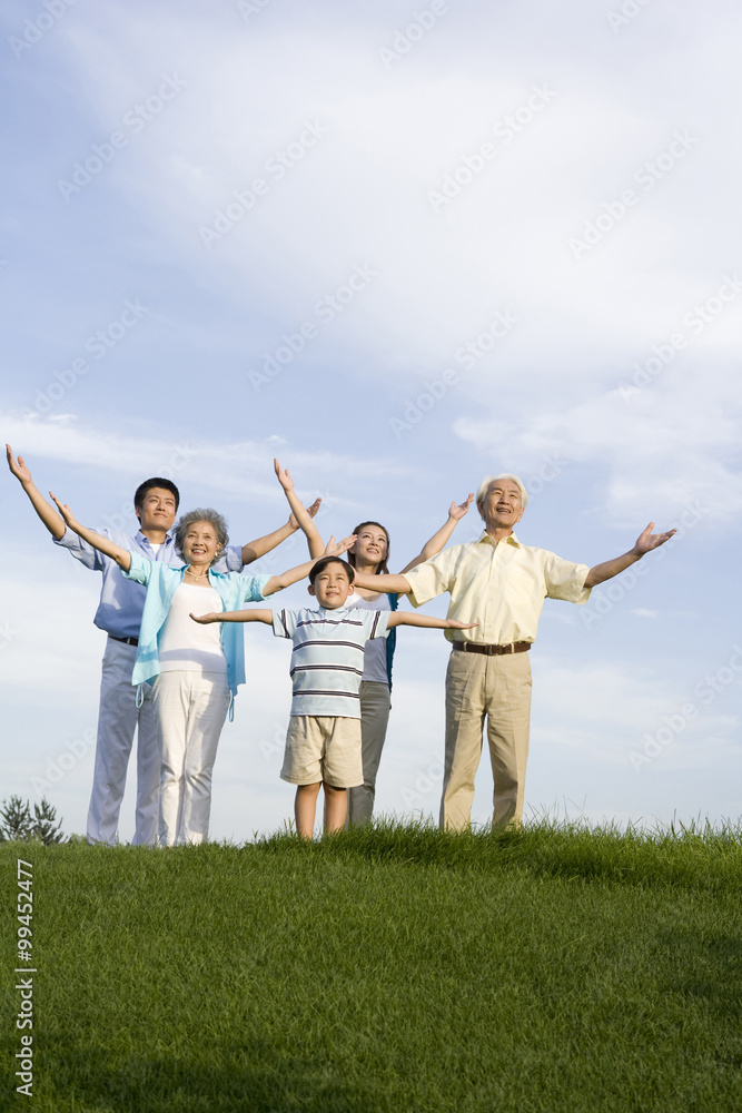 Family standing on the grass, arms outstretched