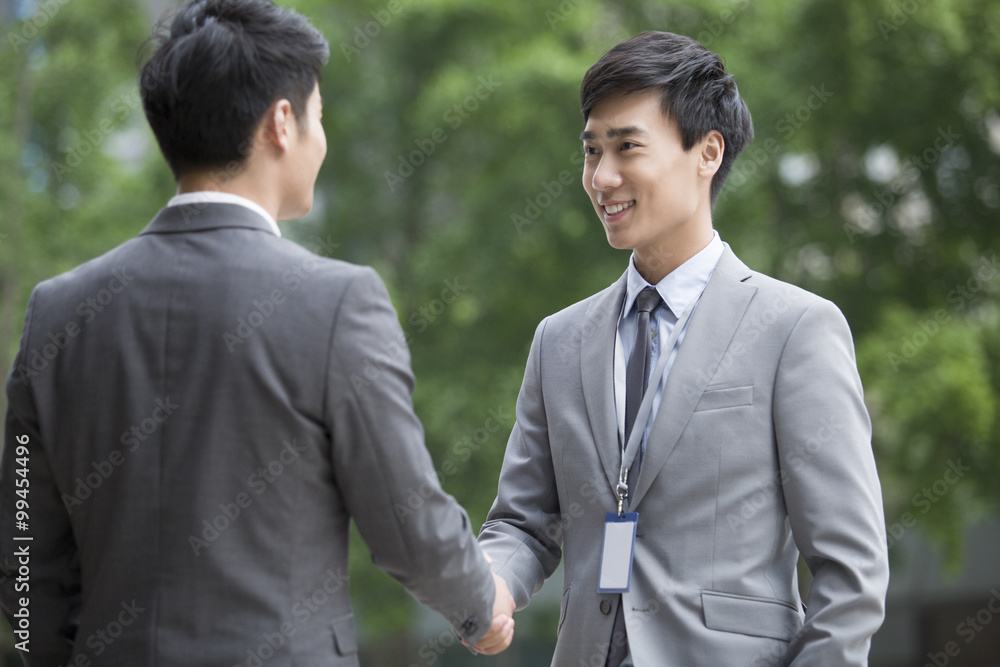 Young business person shaking hands outdoors