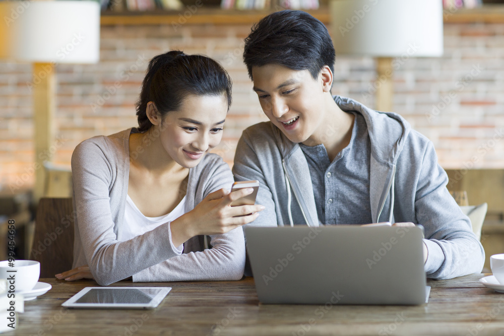 Young couple using smart phone in cafe