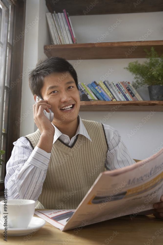 Man Talking On Cellphone Holding A Newspaper