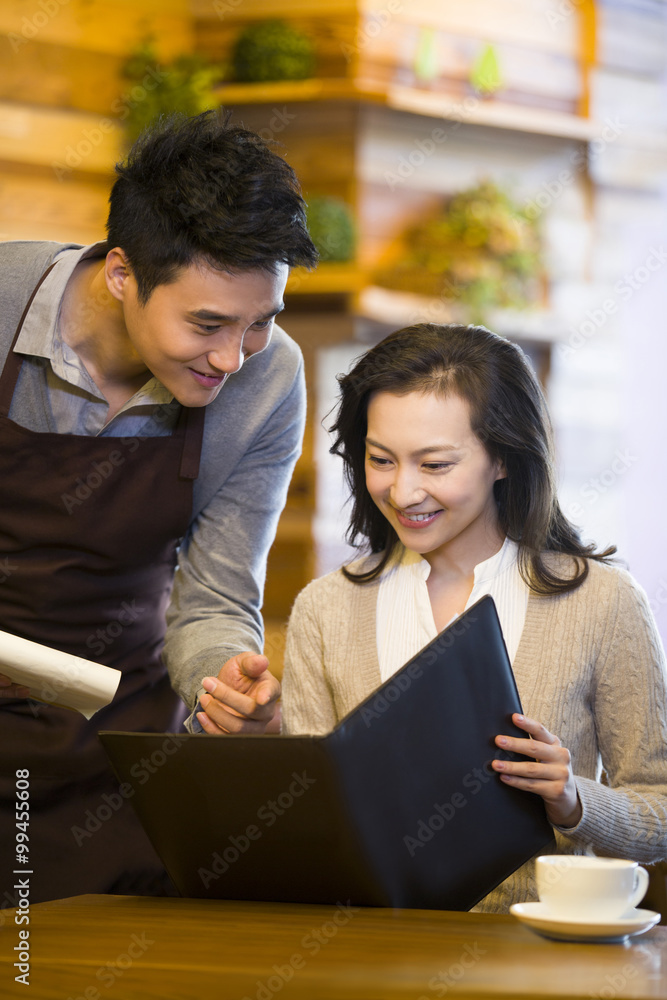 Waiter taking order from woman at restaurant