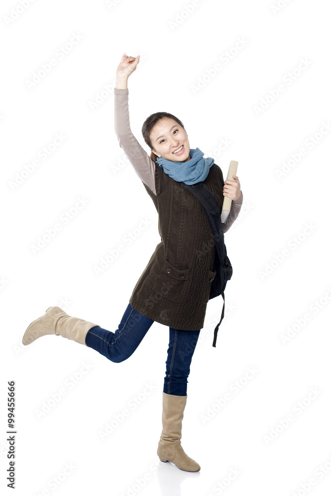 Playful young female student standing on one leg and holding arm up in the air, white background