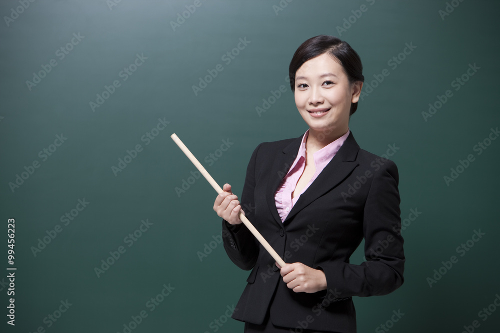 Happy female teacher holding teachers pointer in classroom