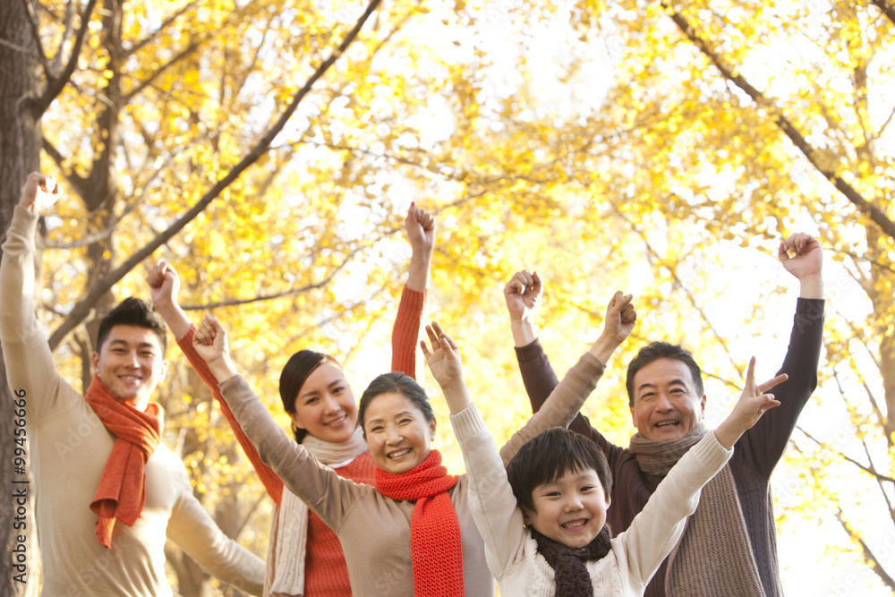 Family with arms raised surrounded by Autumn trees