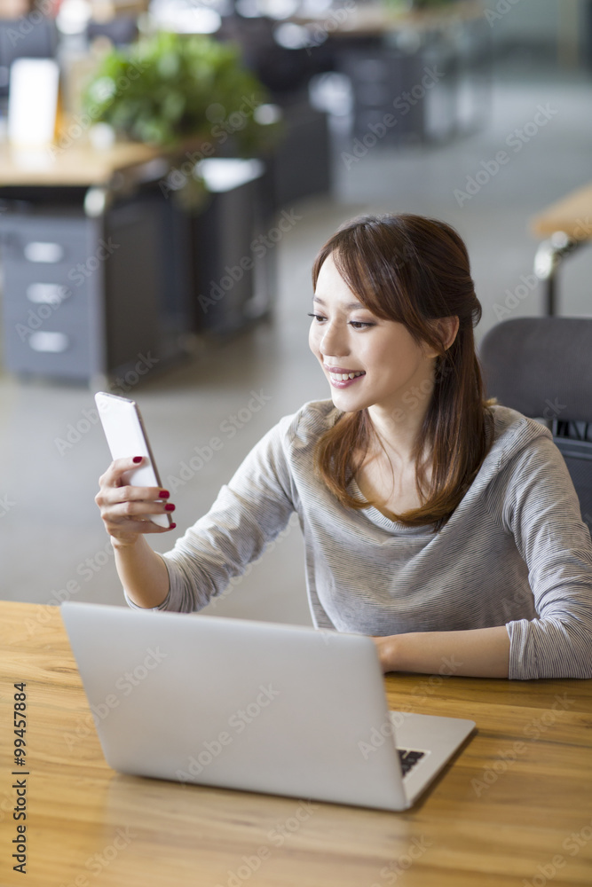 年轻女性在办公室使用智能手机