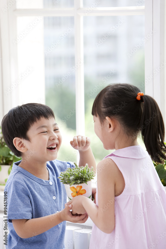 Boy and girl holding the potted plants