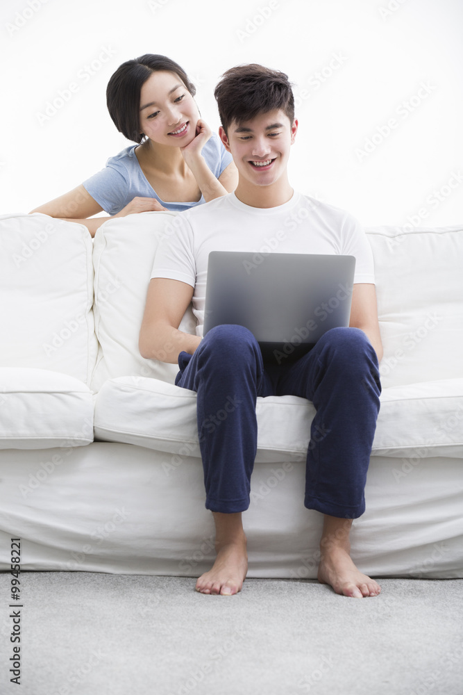 Young couple using laptop on couch