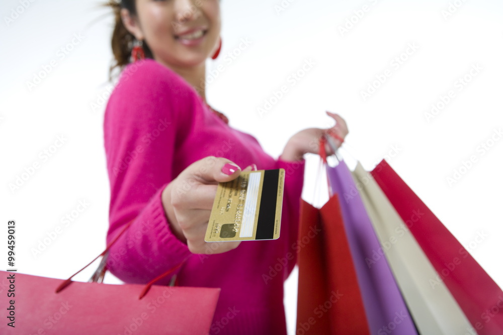 Young woman with shopping bags extending her credit cards