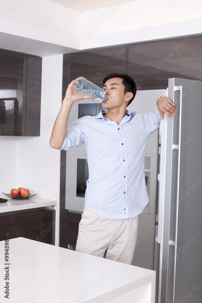 Man drinking a bottle of water in the kitchen