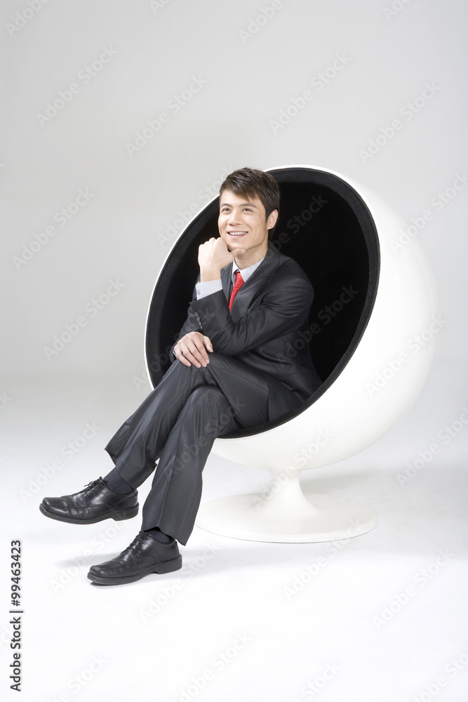 Confident young businessman sitting in a ball chair