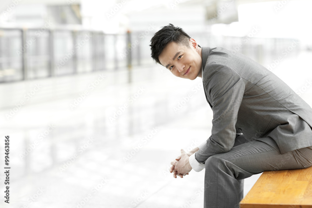 Young businessman sitting on bench at subway station