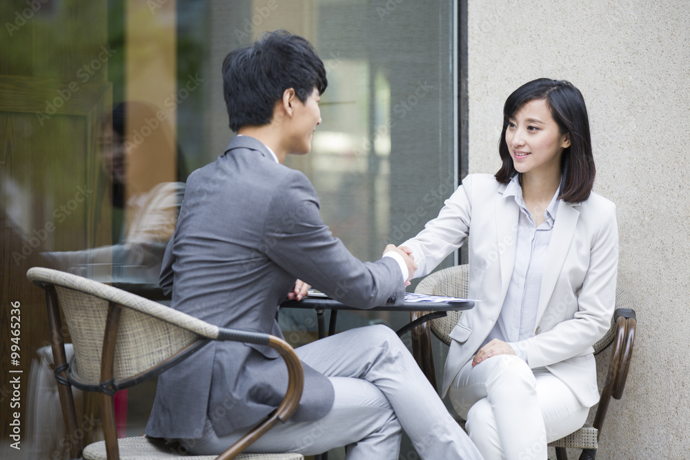 Two business person sitting at outdoor sidewalk café