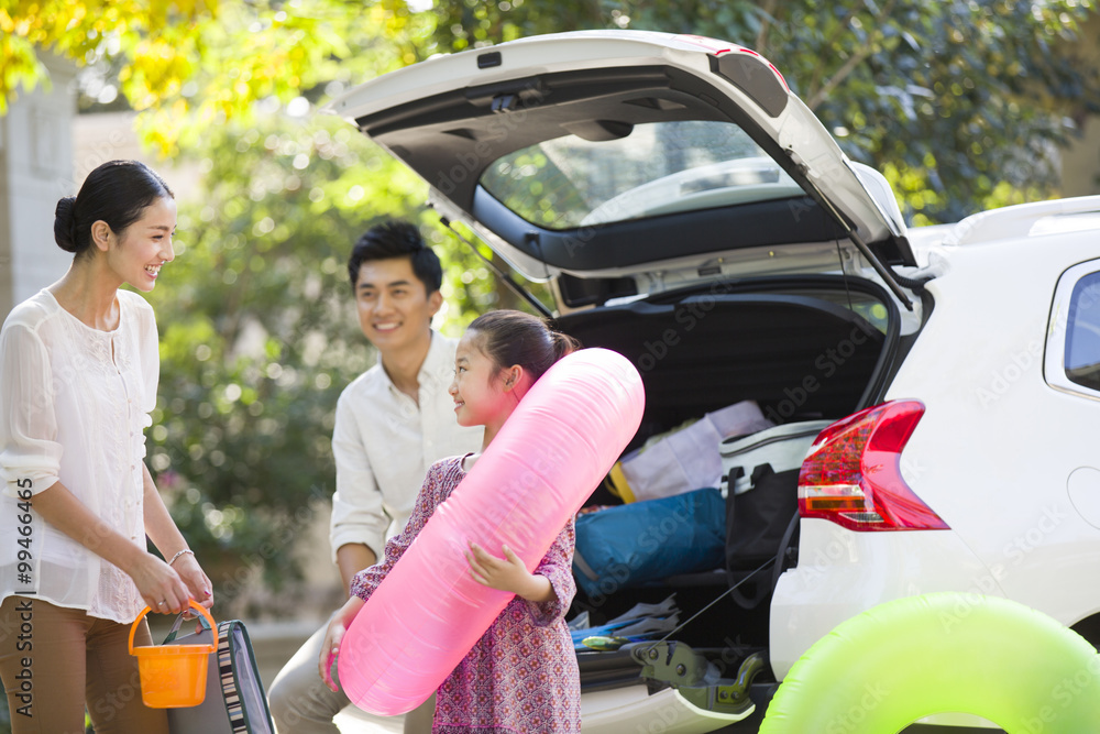 Young family putting water sports equipment into the car