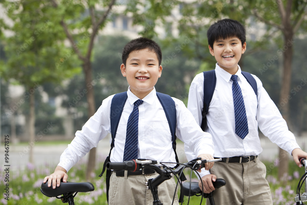 快乐的穿着制服的男生在户外骑自行车