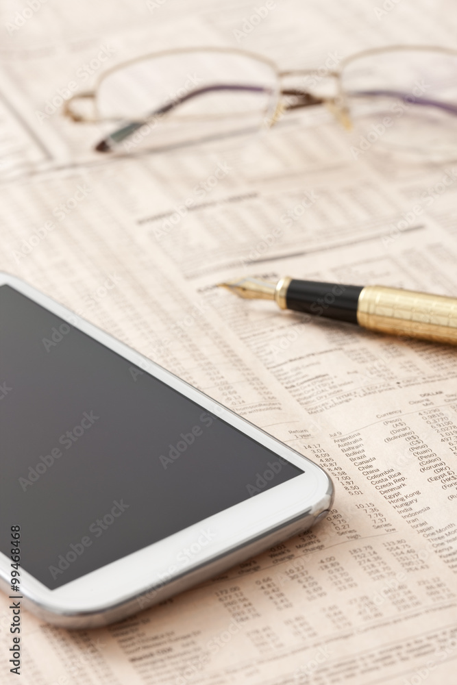 Financial newspaper and mobile phone on desk