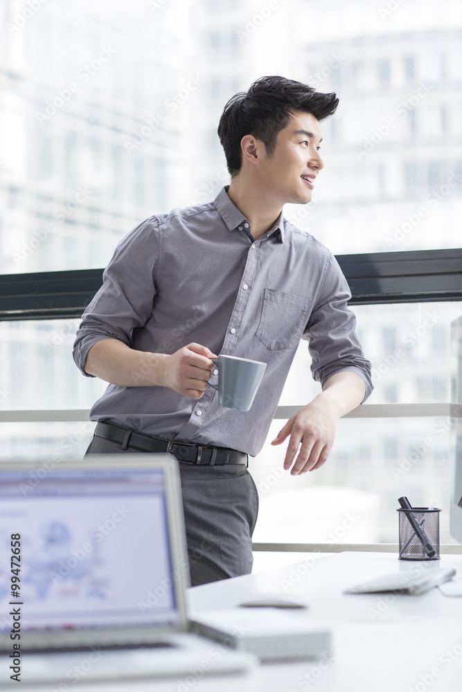 Young businessman drinking coffee in office