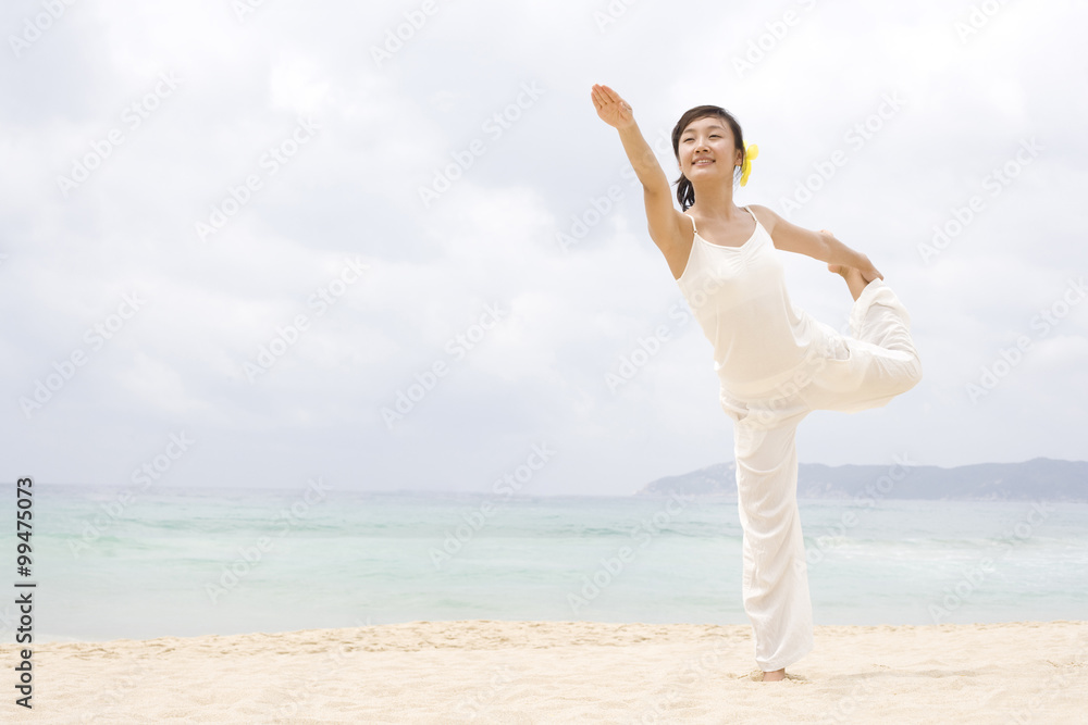 A woman practicing yoga at the beach