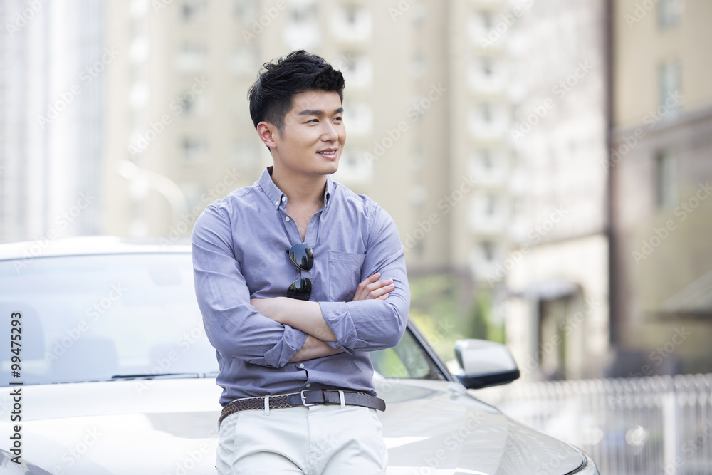 Young man leaning against his car