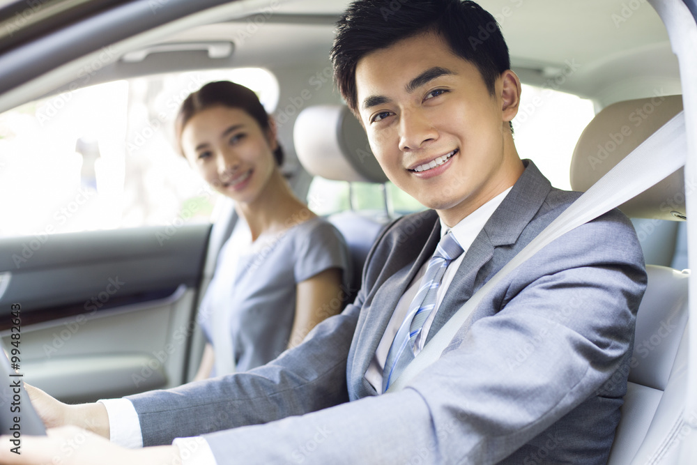 Young businessman driving car with his wife sitting next to him