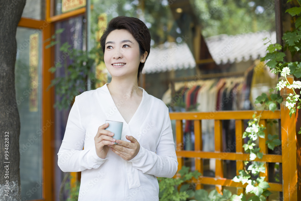 Female shopkeeper standing in doorway with a cup of tea