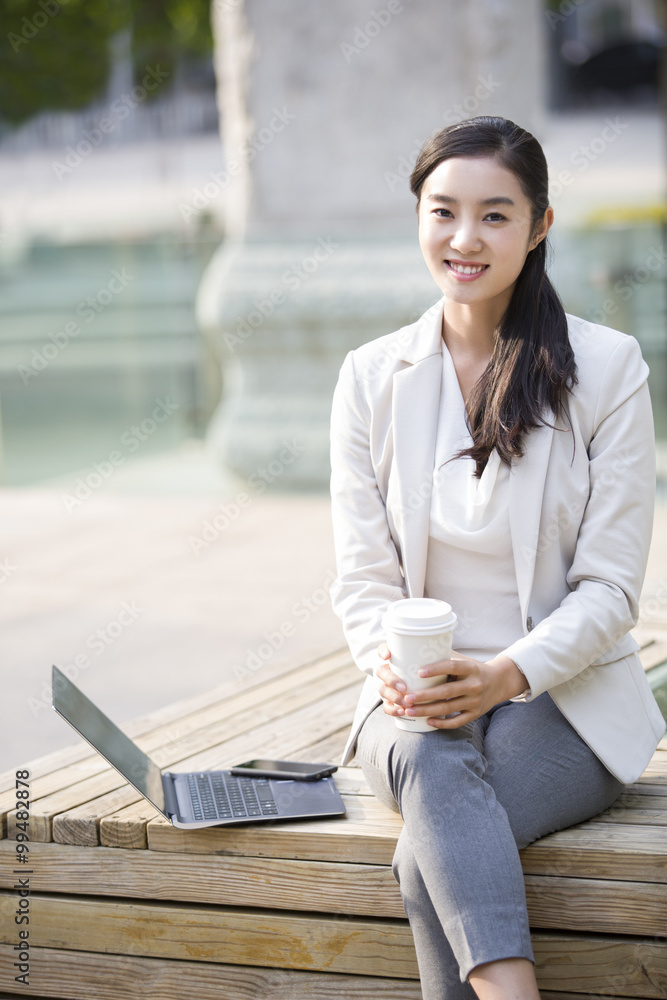 Young businesswoman working with laptop outdoors