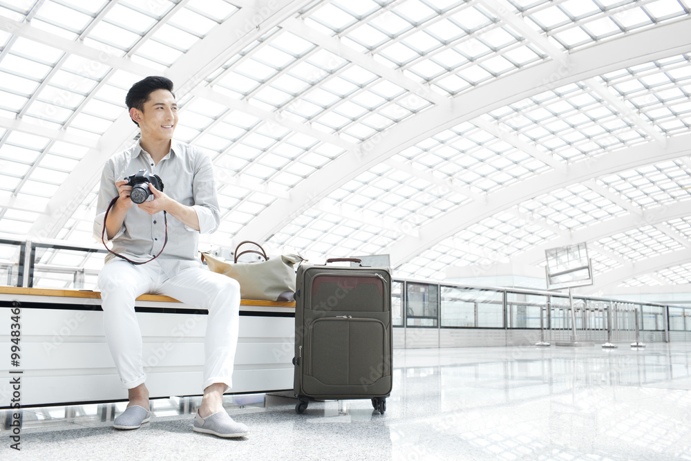 Young man with camera waiting at the airport