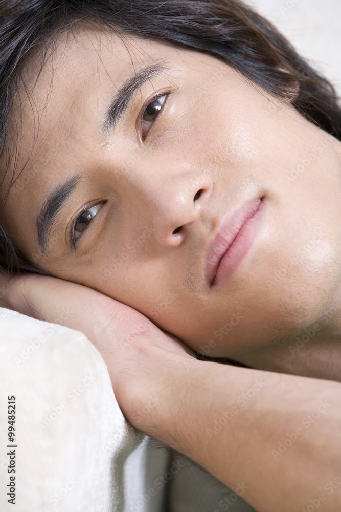 Asian man lying on a sofa