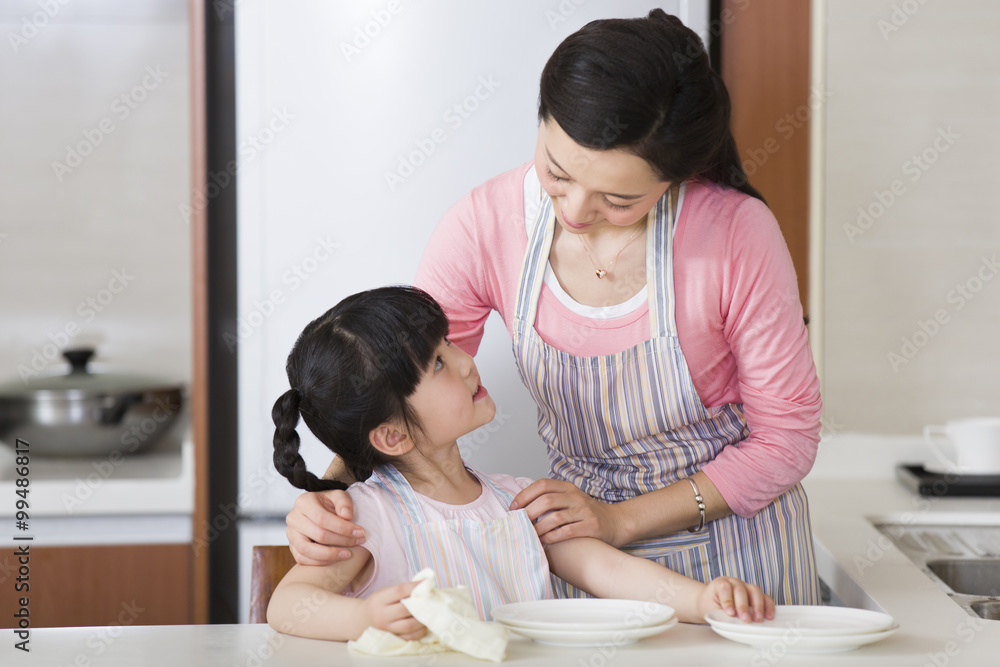 可爱女孩为妈妈烘干盘子