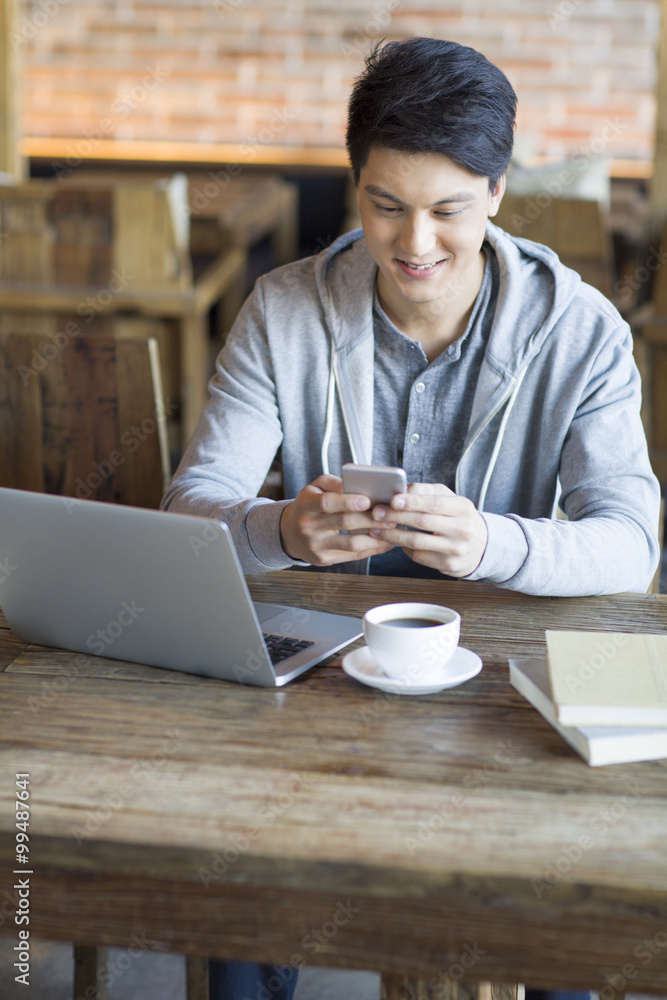 Young man using smart phone in cafe