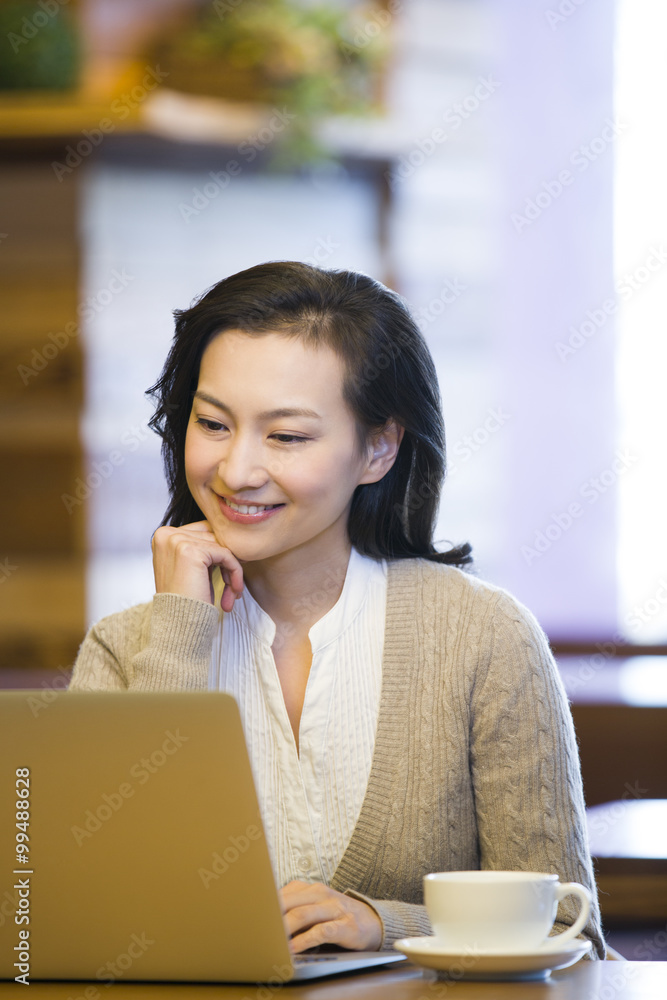 年轻女子在咖啡馆使用笔记本电脑