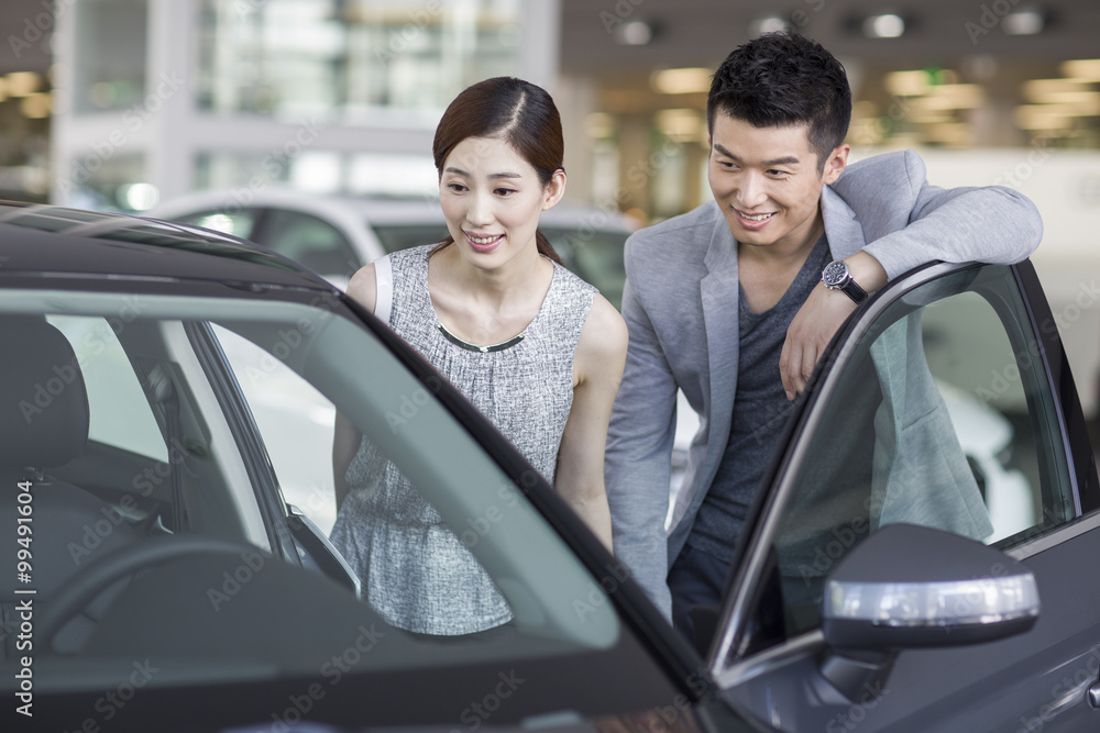 年轻夫妇在展厅里看新车