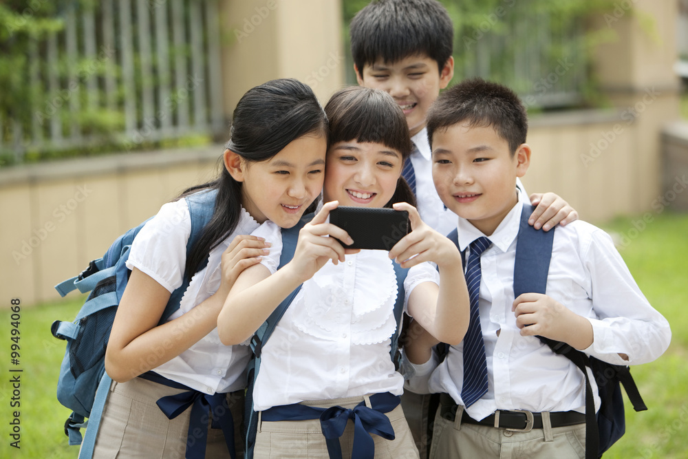 穿着制服的兴奋小学生用智能手机自拍