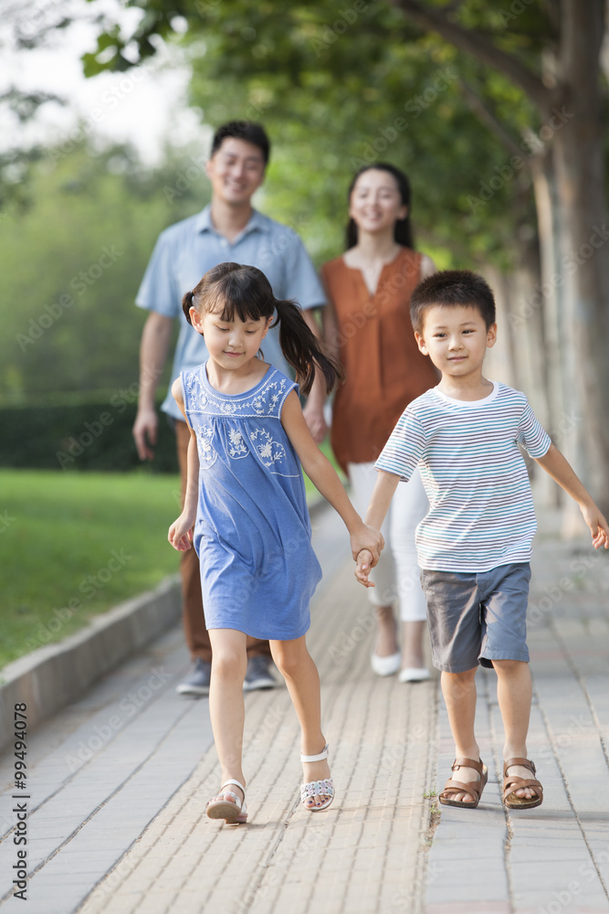 Happy brother and sister holding hands walking