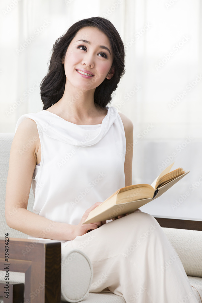 Young woman sitting in armchair and reading