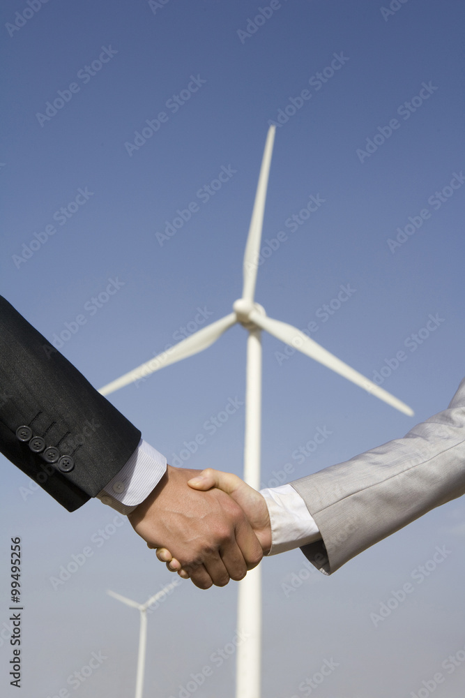 Handshake in front of wind turbines