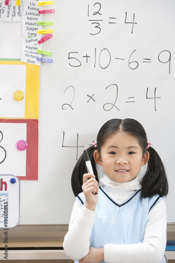 A young student standing proudly in front of her work