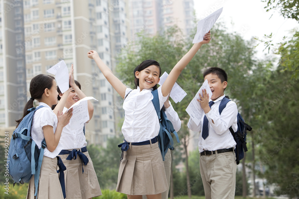 Cheerful schoolchildren in uniform celebrating for their test results