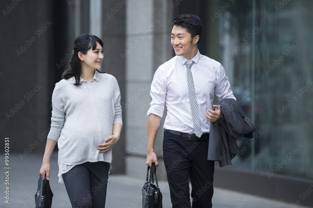 Pregnant businesswoman walking with businessman