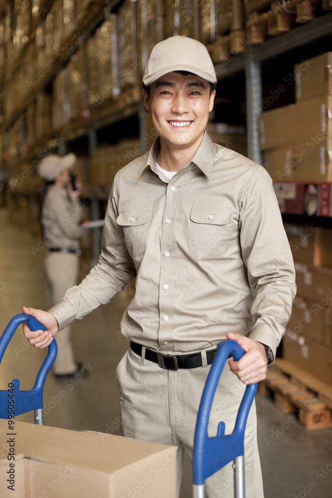 Male Chinese warehouse worker pushing boxes