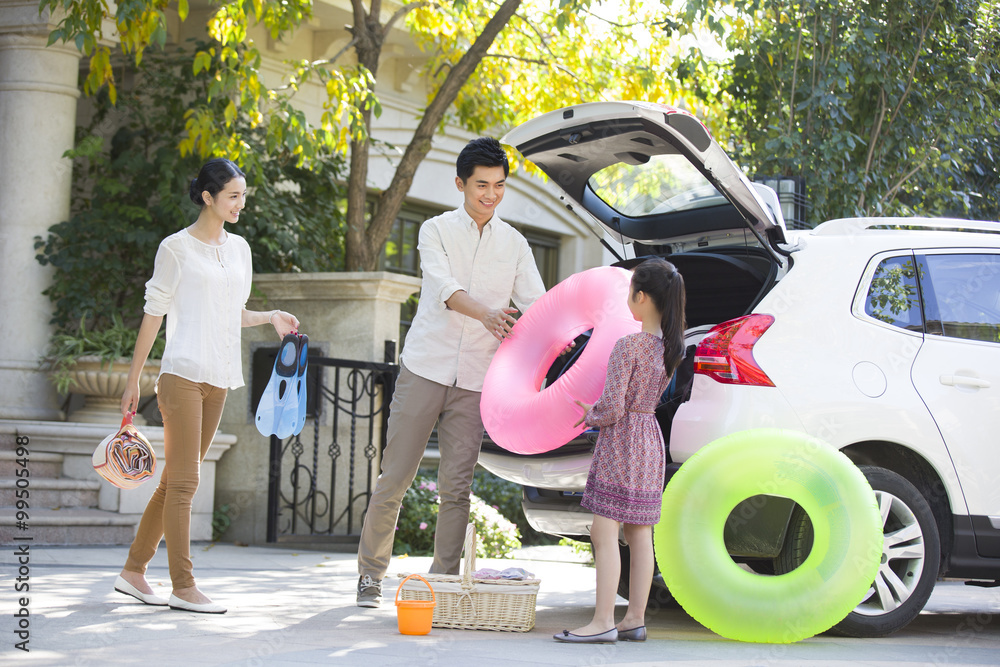 Young family putting water sports equipment into the car